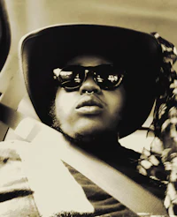 a man wearing a hat and sunglasses in a car